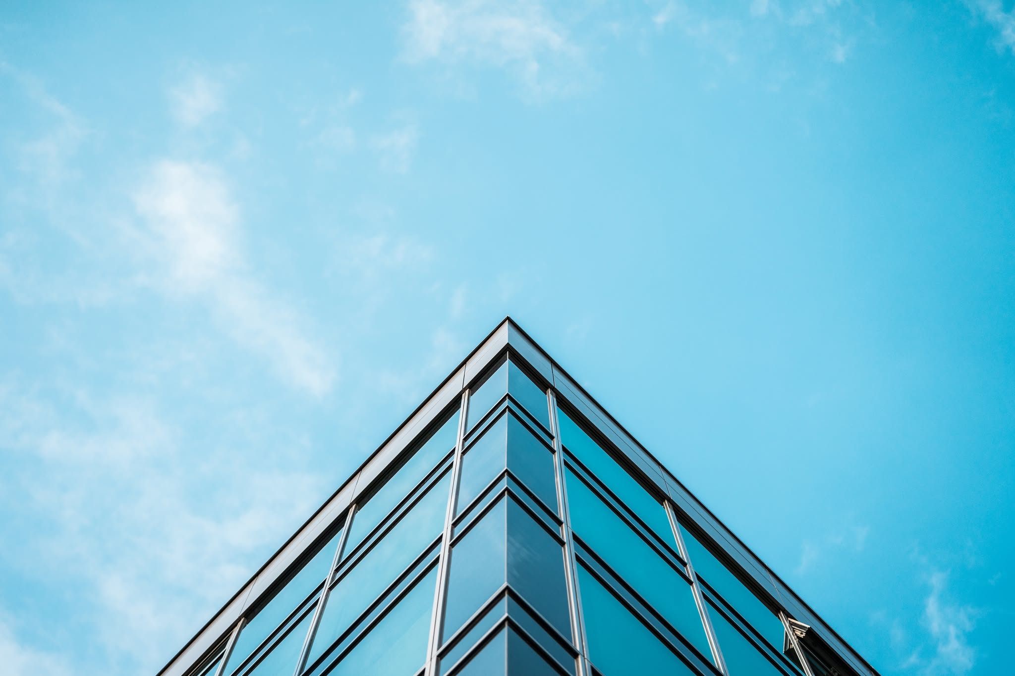 Glass office building facade against blue sky, modern civil engineering architecture
